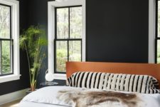 23 a modern bedroom with black walls, a leather upholstered bed and cool lamp cluster looks relaxing and very chic