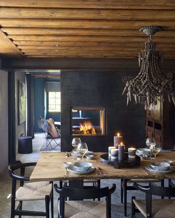 a moody space with a half wall with a glass fireplace that gives coziness to both dining and living room