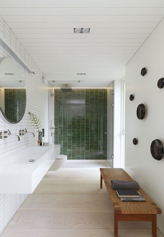 a stylish wicker bench and green tiles in the shower creat a natural ambience in the bathroom