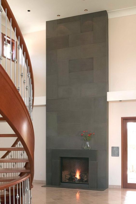 a modern fireplace clad with dark tiles and metal that matches looks very bold in a neutral space