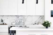 24 a modern white kitchen with a marble backsplash, black stools, lamps and legs