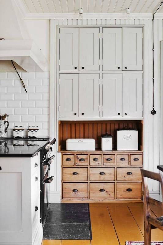 a wooden apothecary cabinet can stand out in a neutral kitchen