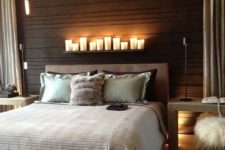 25 a modern bedroom with a headboard wall clad with dark wood and a shelf with candles to highlight it