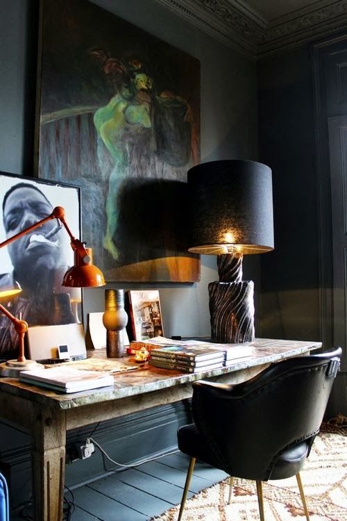 a refined home office with black walls, floor and furniture and gorgeous artworks for an art lover