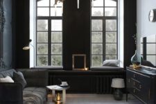 25 a small refined living room with two black walls, a black sofa and sideboard, modern lamps and lots of lght