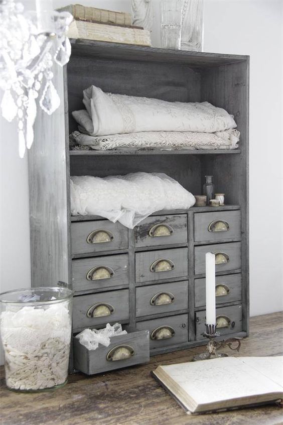 an apothecary cabinet painted light grey and renovated into a linen storage item