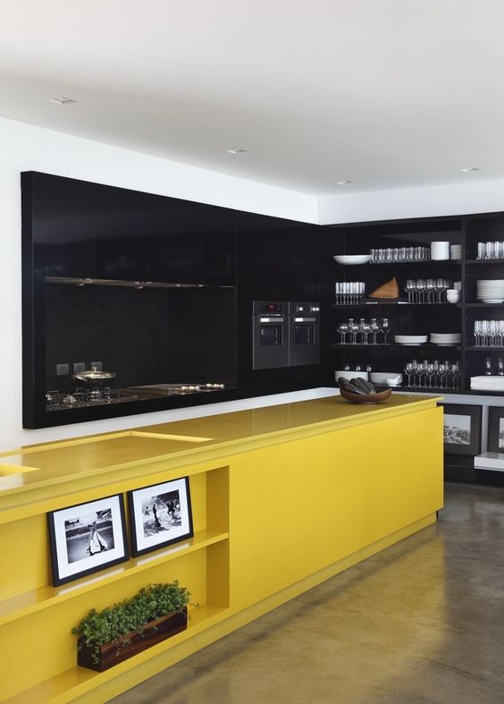 a moody black kitchen with a bold yellow kitchen island with lots of storage