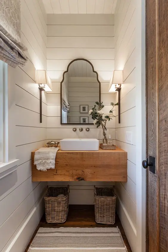 a rustic butcher's countertop makes a statement in this powder room, and baskets under it add a cozy feel