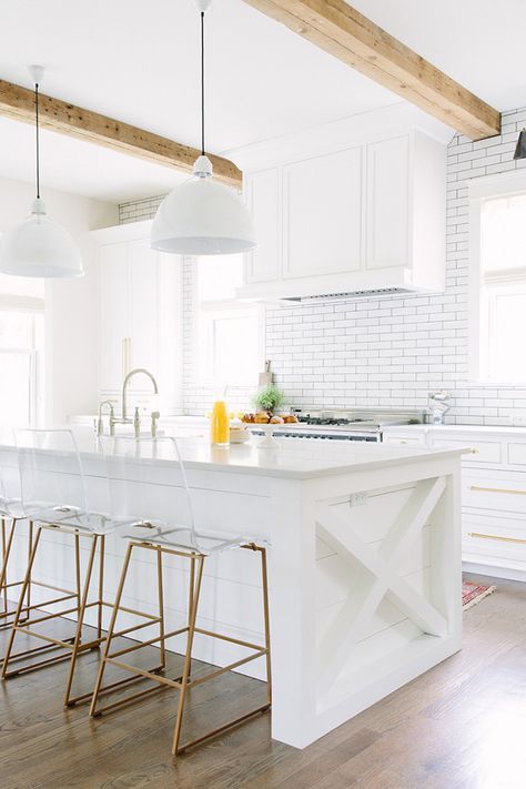 a white rustic kitchen with a subway tile backsplash and wooden beams to make it more eye-catching