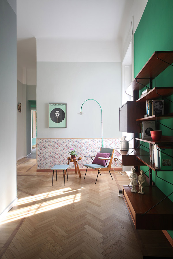 This colorful space is done with a green statement wall, colorful wallpaper and lots of floating shelves and drawers