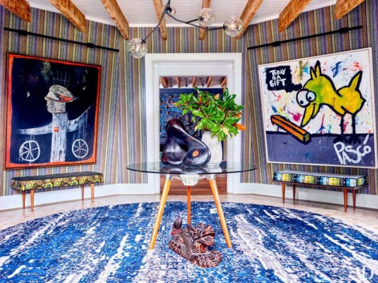 The entry is done in the bold shades of blue, with colorful upholstered benches and very bold artworks