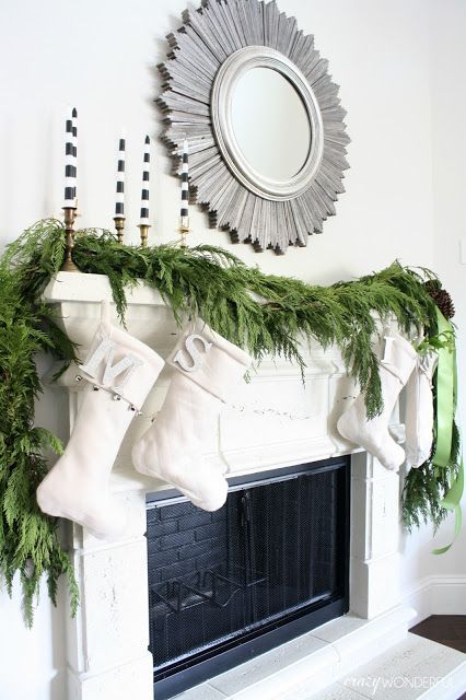 a lush evergreen garland, creamy stockings and striped candles make up a modern look with a rustic feel