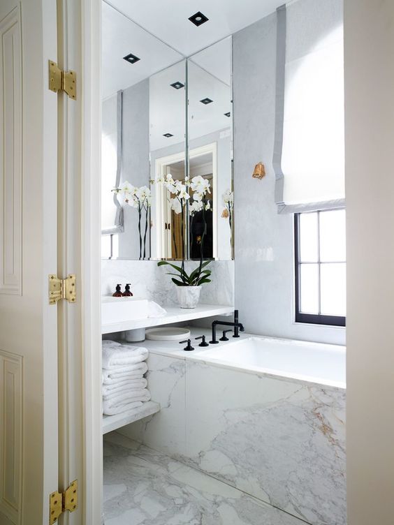 all-marble bathroom with a large mirror that takes almost the whole wall