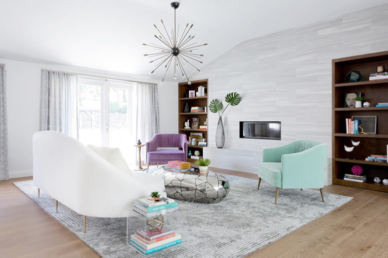 the first living room is done in white, there is colorful furniture, built-in bookcases and a mirror pebble table