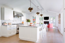 03 The kitchen is airy and light-colored, there’s a sitting space with coral chairs and a built-in fireplace