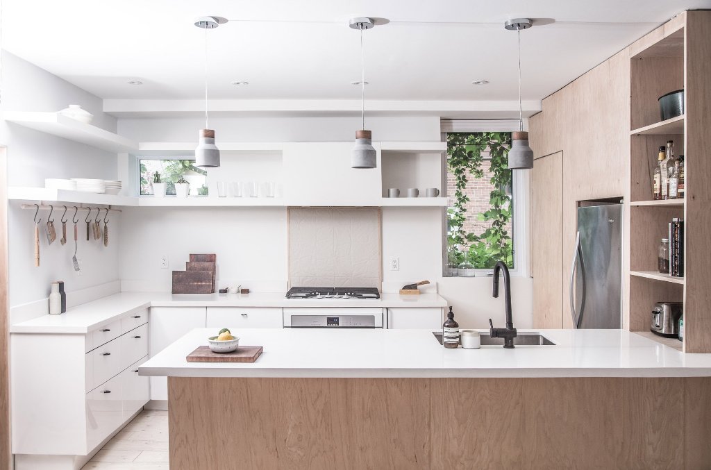 The kitchen is done in white and with light-colored wood, there are modern concrete pendant lamps and two small windows to bring light in