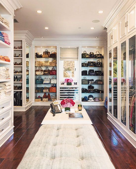 A large walk in closet with open shelving and mirrored wardrobes, lots of lights