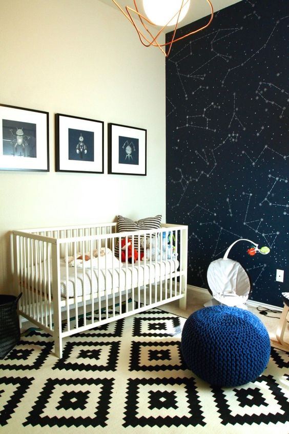 a space-themed nursery with a constellation statement wall, fun artworks and a navy pouf