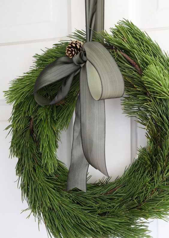an elegant evergreen wreath with a pinecone and a grey ribbon bow