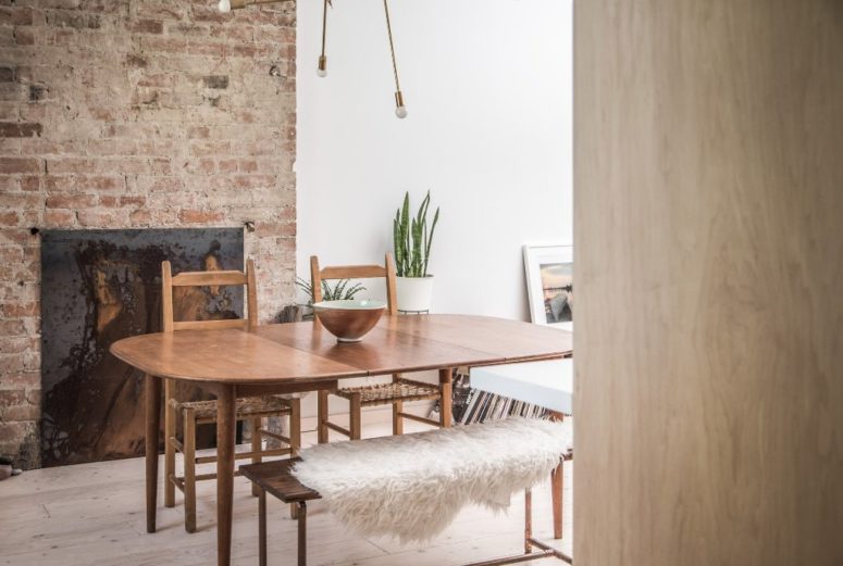 The dining space is done with a mid-century modern dining set, a burst lamp and a brick wall with a built-in fireplace