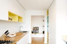 04 The kitchen is minimalist, with sleek white cabinets, colorful inside of cabinets, butcher’s block tops
