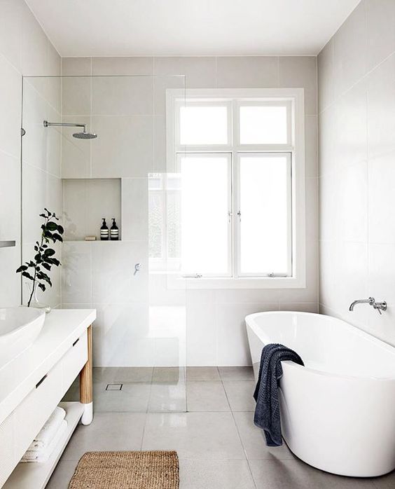 a clean minimalist bathroom with natural wood and jute touches and a grey tile floor
