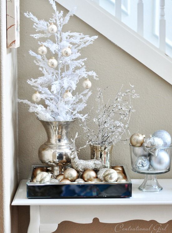 a glam Christmas display with gold and silver ornaments, a deer and snowy branches