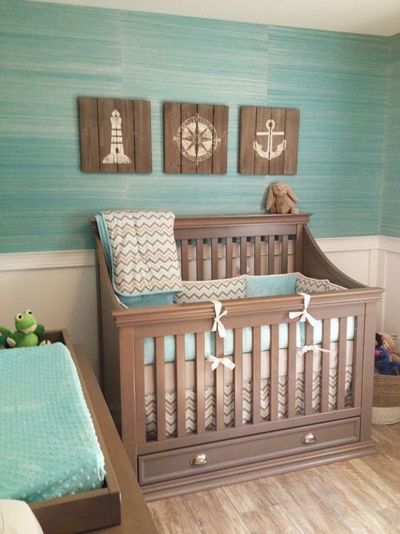 Ocean themed nursery with reclaimed wood artworks and a turquoise wall and bedding