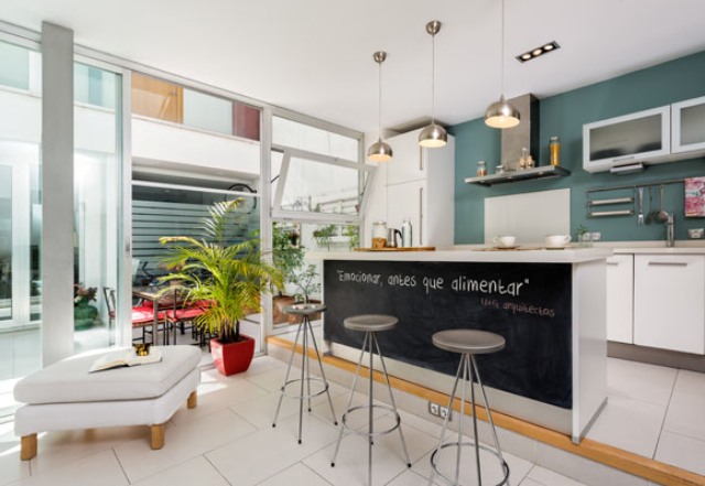 The kitchen features a chalkboard kitchen island and it's located on a platform to separate the space