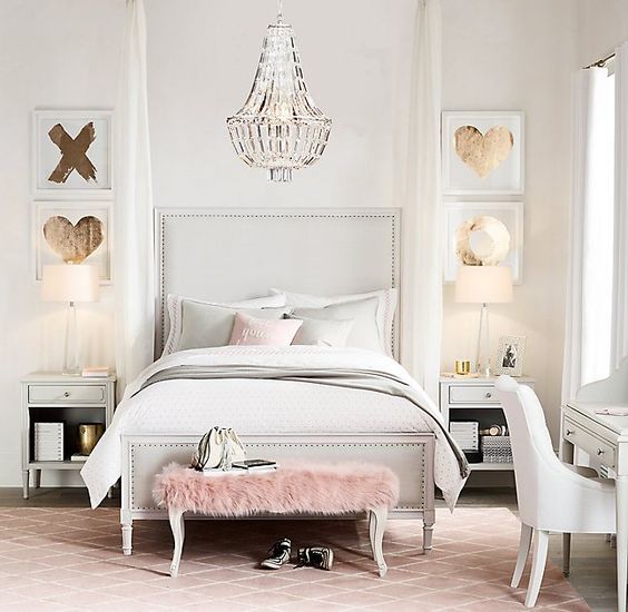 a bedroom done in cream and light grey, a pink fur bench and gold touches