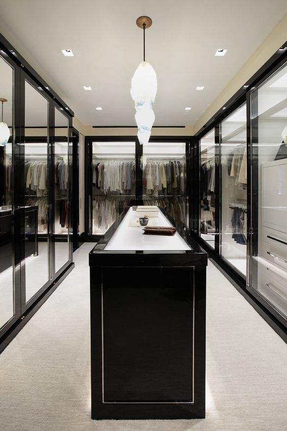 A stunning walk in closet with framed glass doors and lots of light looks very spectacular
