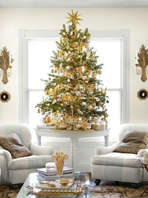 a small tabletop Christmas tree with gold and white ornaments looks contrasting and festive