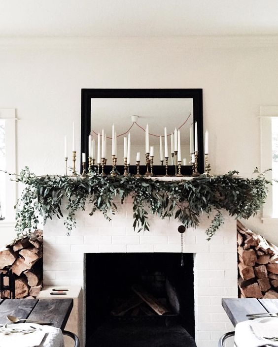 elegant mantel decor with an evergreen garland and lots of candles is easy to recreate and looks cool