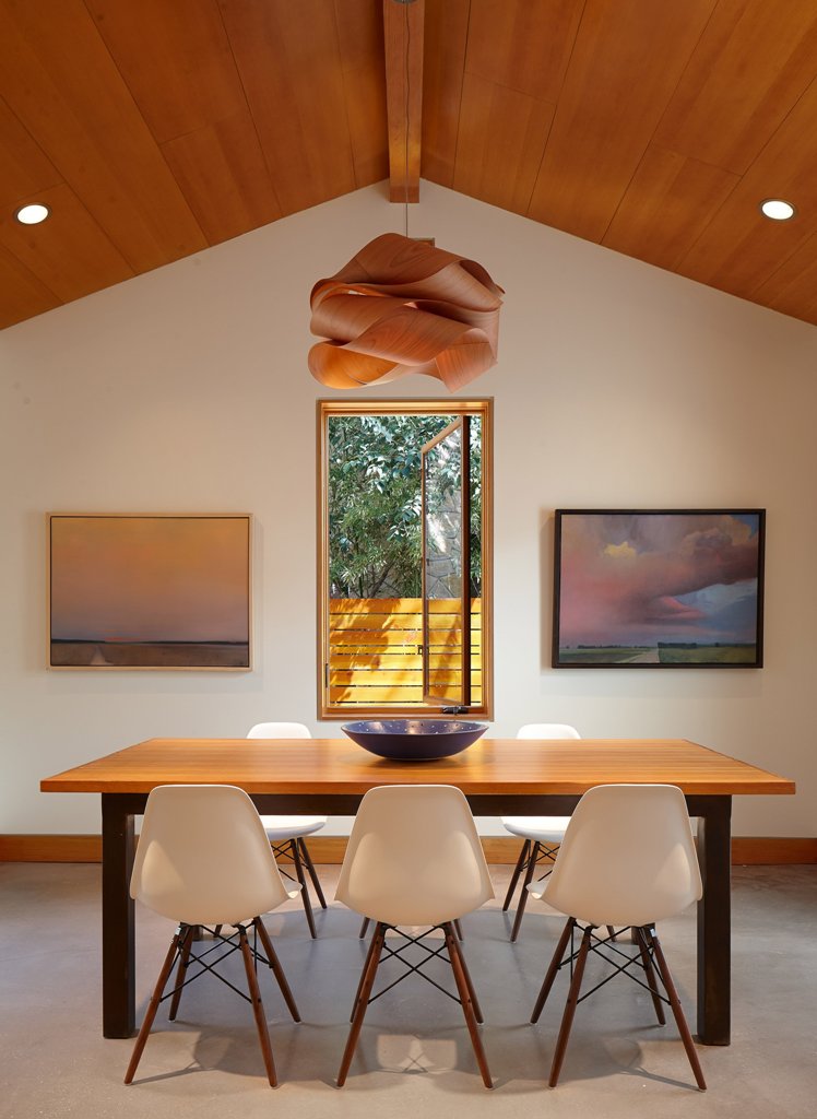 The dining space is marked with artworks, a window and a very eye-catching pendant lamp of curved plywood