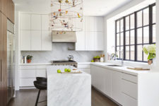 07 The kitchen is done with sleek white cabinets, a wooden wall with built-in appliances and marble countertops