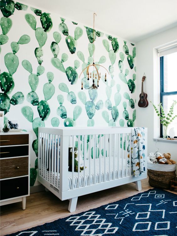 a desert-themed nursery with a watercolor cactus wall, a reclaimed wood dresser