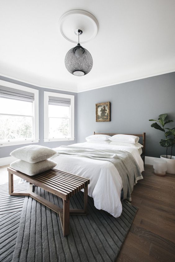 a minimalist bedroom in the shades of grey and white, a wooden bed and bench for a warmer feel