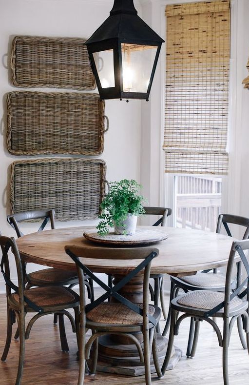a rustic space with baskets on the wall, a wooden dining set and some neutral Roman shades