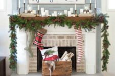 08 a rustic mantel with an evergreen and pinecone garland, candles and a sign over it