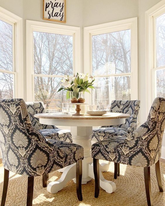 a traditional breakfast nook with a pedestal round table and printed upholstered chairs