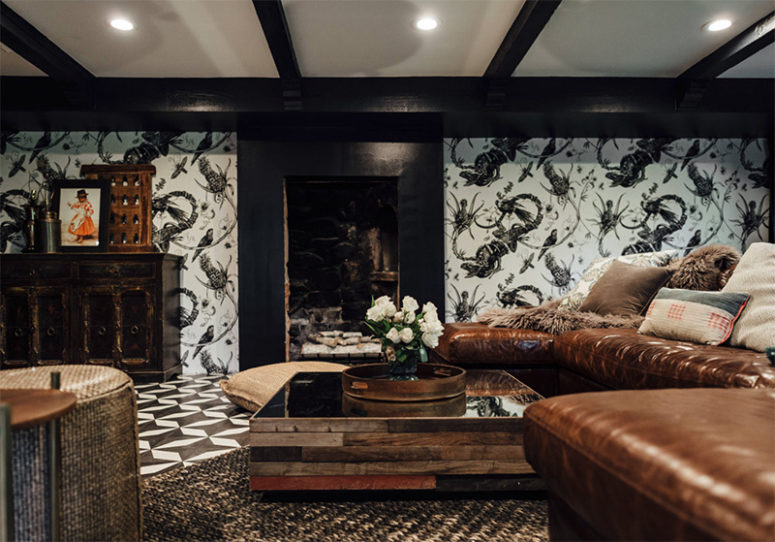The living room is black and white, with eye-catchy wallpaper, mosaic floors and brown leather furniture