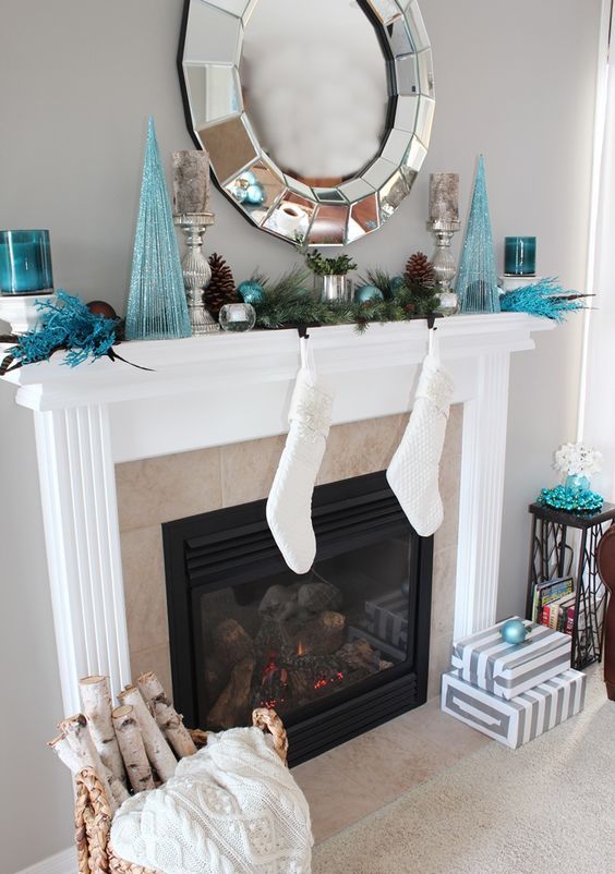 a glam mantel with a large mirror, blue trees, ornaments and candle holders and pinecones