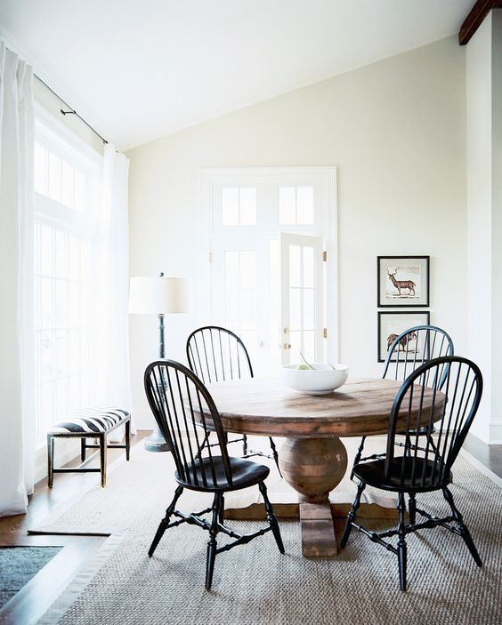a large vintage wood pedestal table and vintage black chairs for an eye-catchy breakfast space