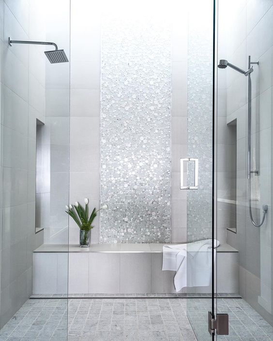 a shower and steam room done with grey tiles and shiny silver accents looks very glam and cute