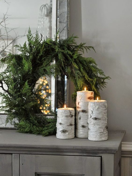 an evergreen wreath with birch branch candle holders for a rustic feel in your space