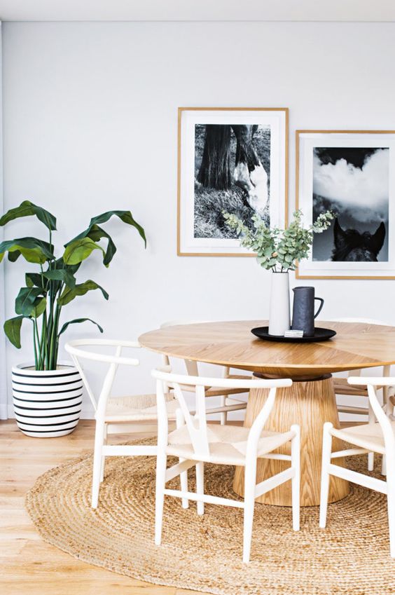 a modern breakfast nook with a simple wooden pedestal table, some chairs and a jute rug looks very natural