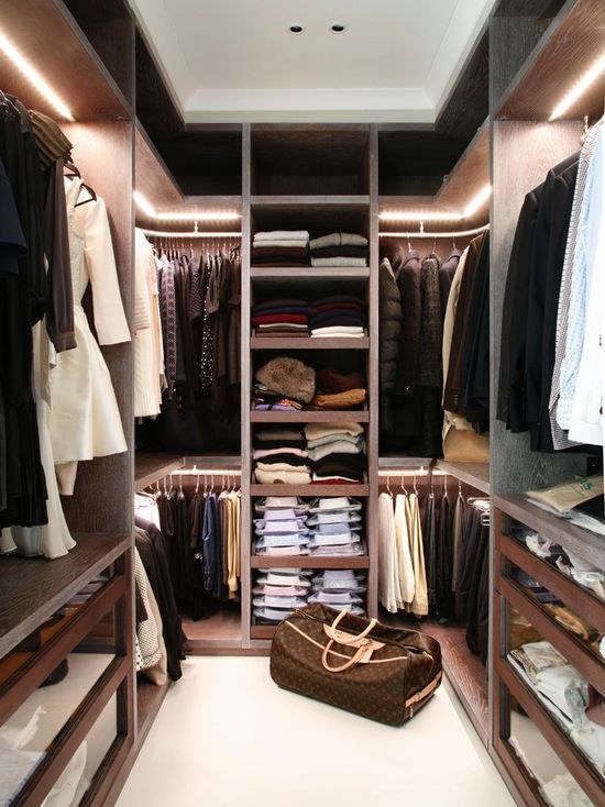 a trendy modenr closet with natural wood shelves and additional light and glass drawers