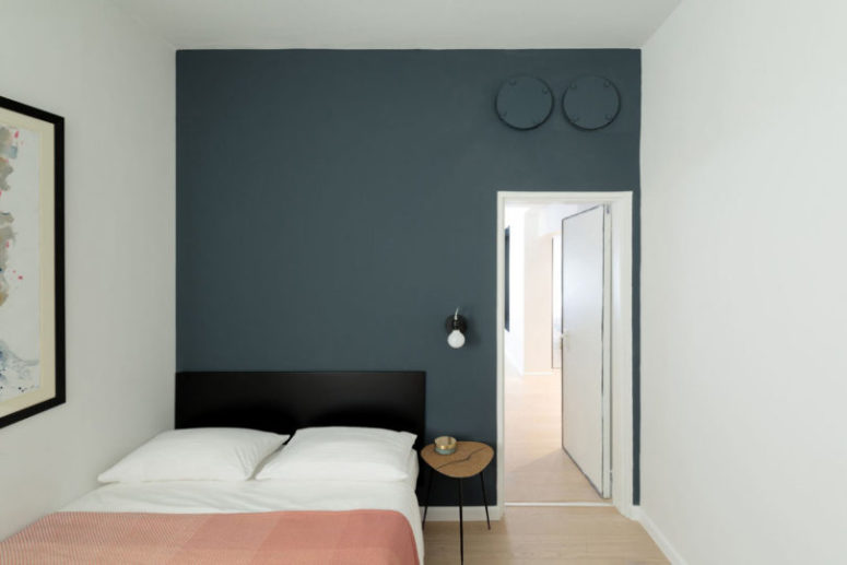 The second bedroom is done with a smoky blue statement wall, a large bed and an artwork