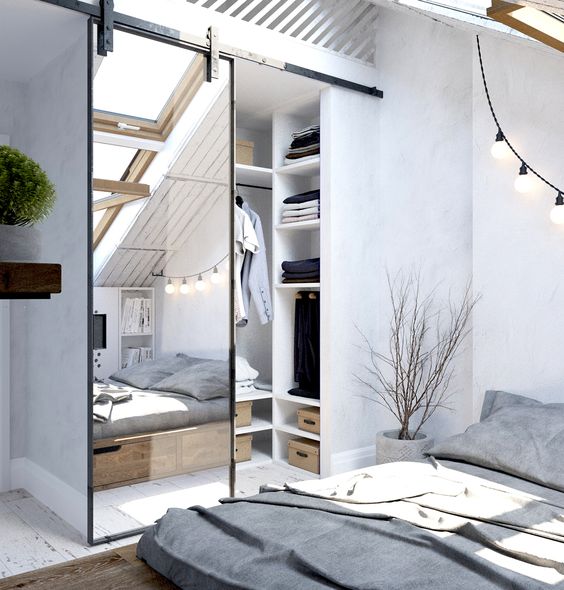 a Scandinavian bedroom with an attic closet, which is separated with a mirror barn door