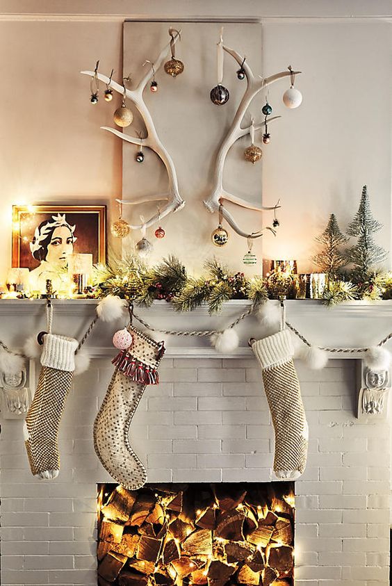 some stockings, an evergreen garland with lights, candles and antlers with Christmas ornaments